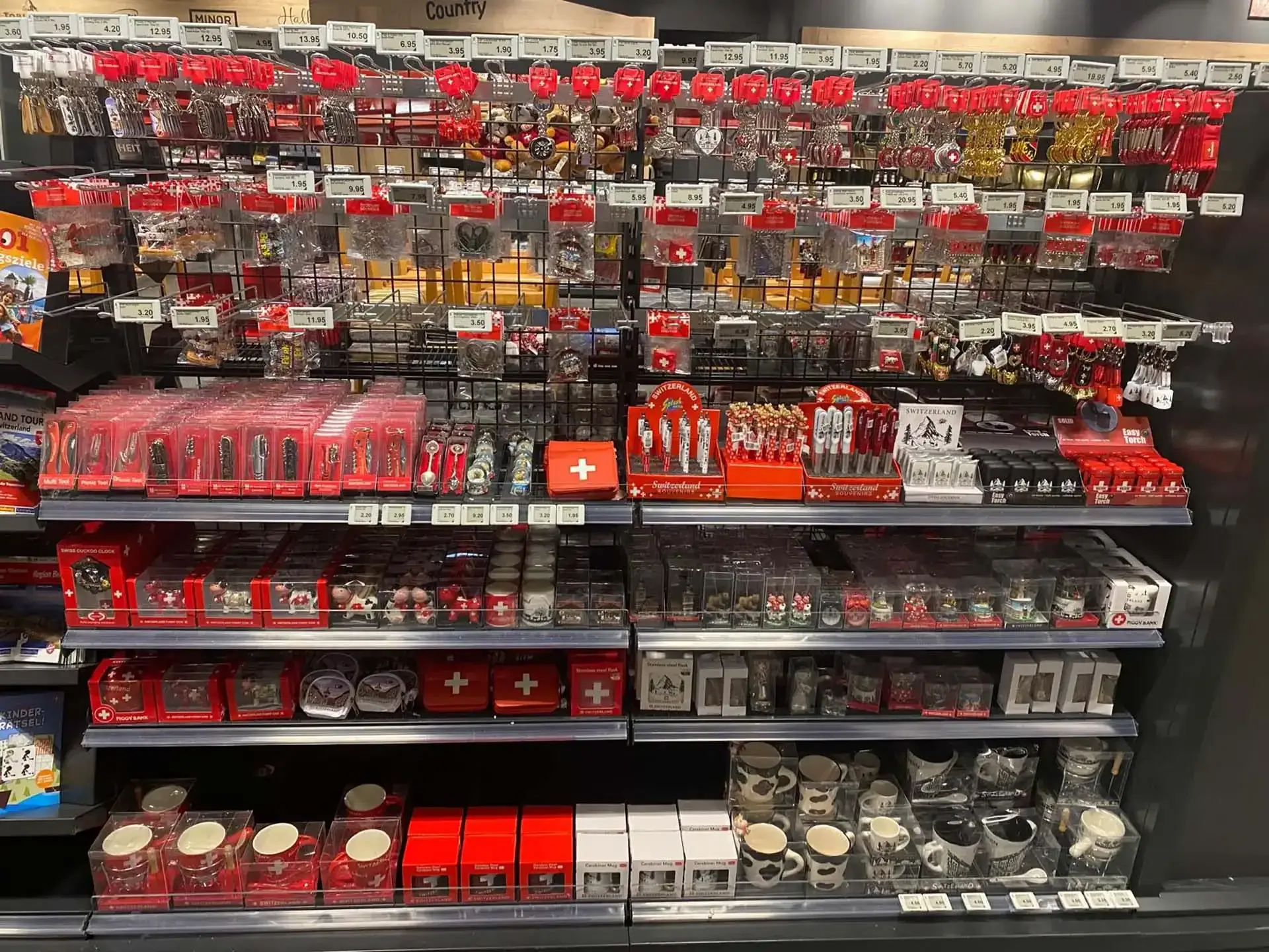 Die Regale sind gefüllt mit Schweizer Souvenirartikeln wie Tassen, Schlüsselanhängern und kleinen Figürchen. Die Regale sind gefüllt mit Schweizer Souvenirartikeln wie Tassen, Schlüsselanhängern und kleinen Figürchen.