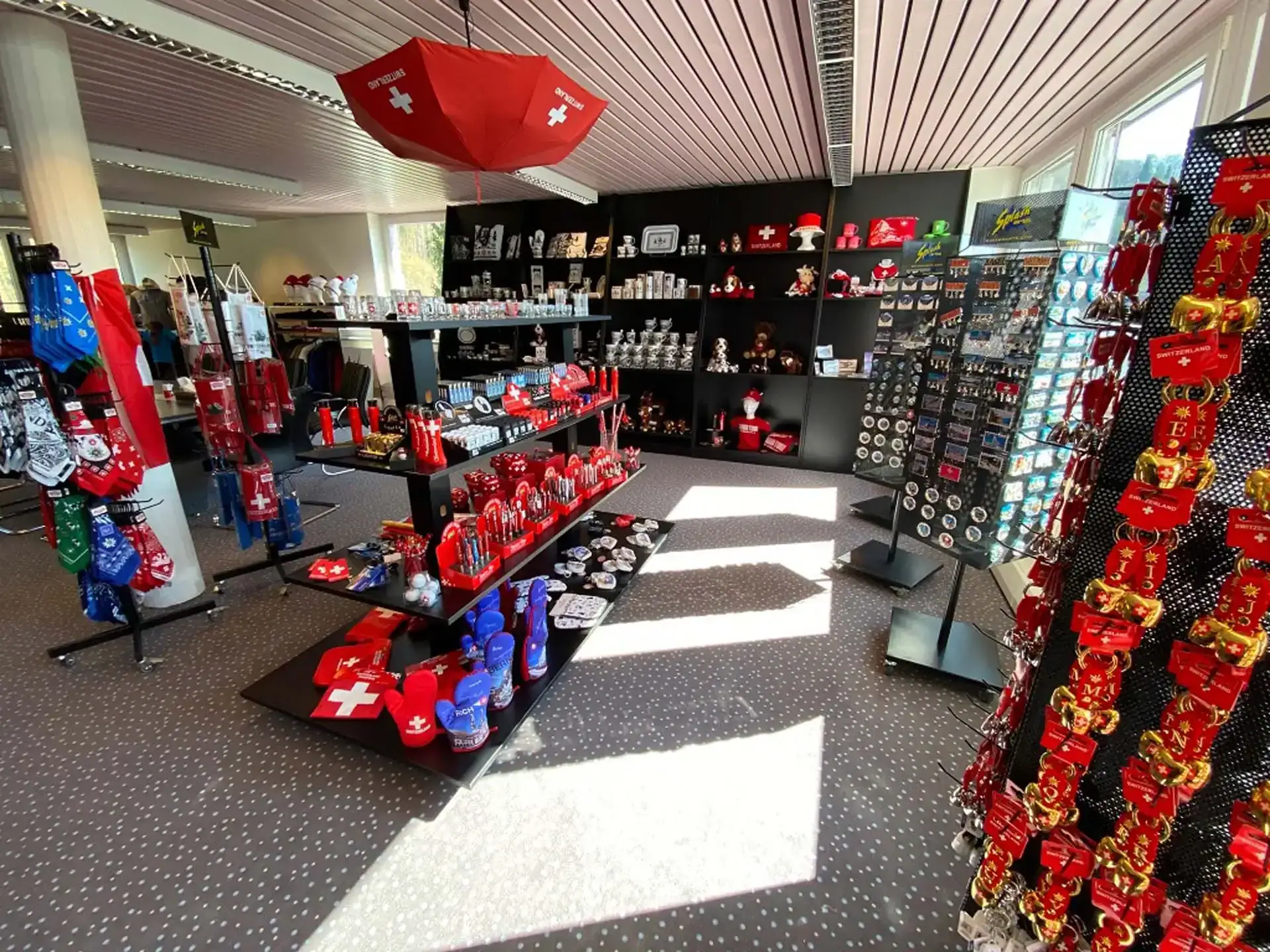 Geschenkladen mit Schweizer Souvenirs, darunter Tassen, Flaschen und Schlüsselanhänger, die ausgestellt werden. Geschenkladen mit Schweizer Souvenirs, darunter Tassen, Flaschen und Schlüsselanhänger, die ausgestellt werden.