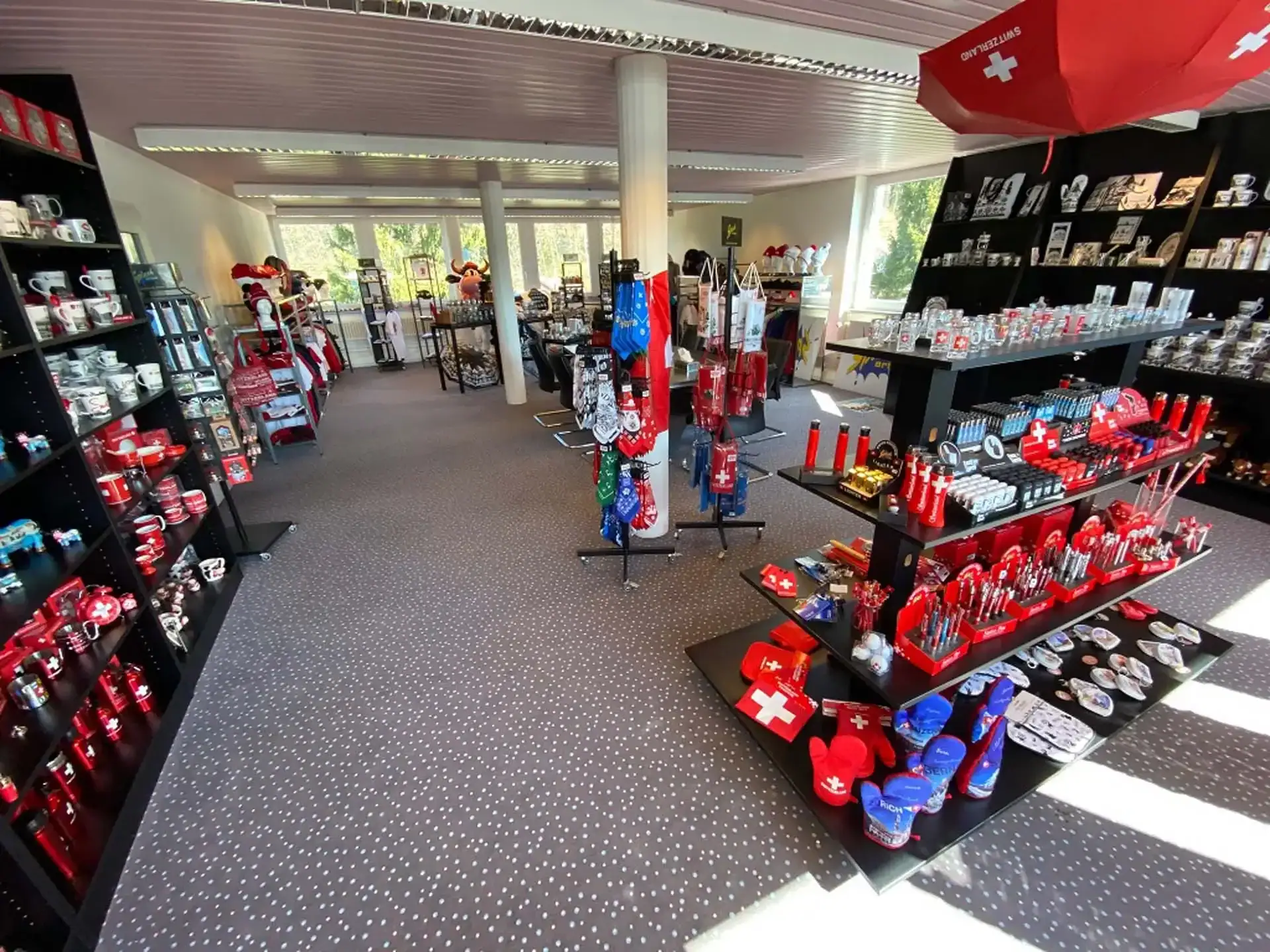 Geschenkladen mit Regalen mit Schweizer Souvenirs, Tassen und rot-weissen Artikeln. Geschenkladen mit Regalen mit Schweizer Souvenirs, Tassen und rot-weissen Artikeln.