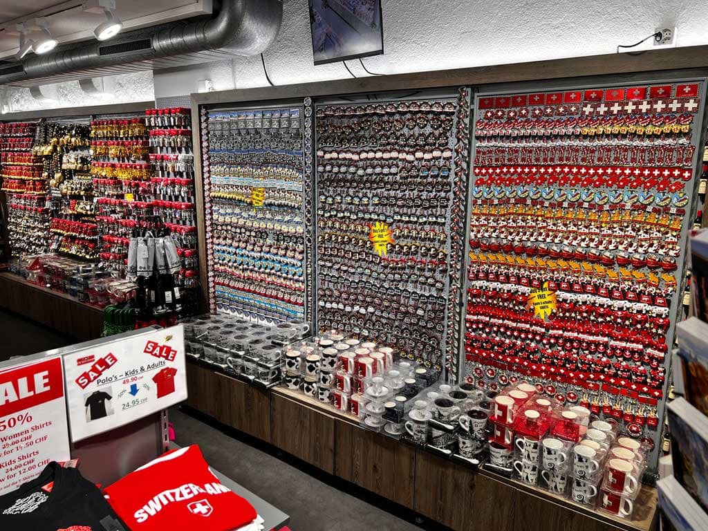 Wanddisplay mit Souvenir-Schlüsselanhängern und Tassen, mit Verkaufsschildern in einem Geschäft. Wanddisplay mit Souvenir-Schlüsselanhängern und Tassen, mit Verkaufsschildern in einem Geschäft.