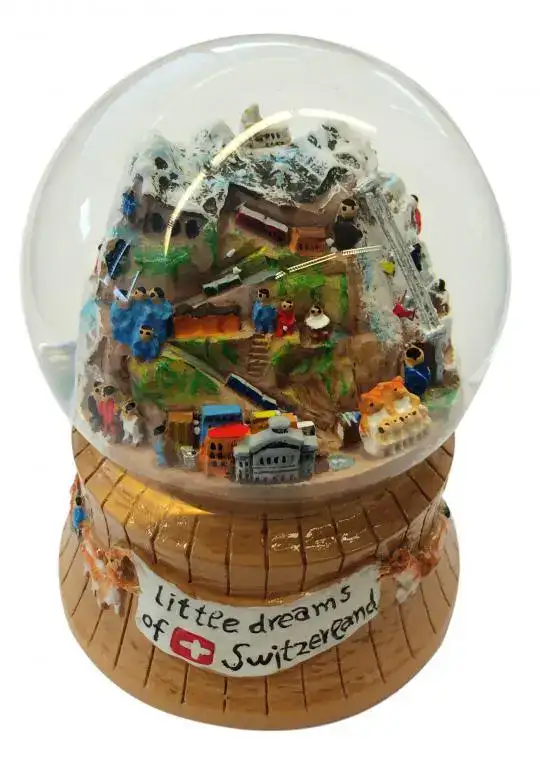 Eine Schweizer Schneekugel mit Bergen, Zügen und grosshandel schweiz auf dem Sockel.