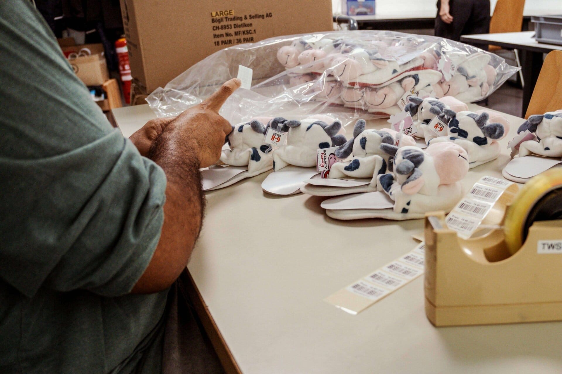 20250814_Splash_Auftrag-11 Spielzeug-Cowboyhüte mit Kuh-Motiv auf einem Tisch in einer Fabrikhalle, Nahaufnahme.